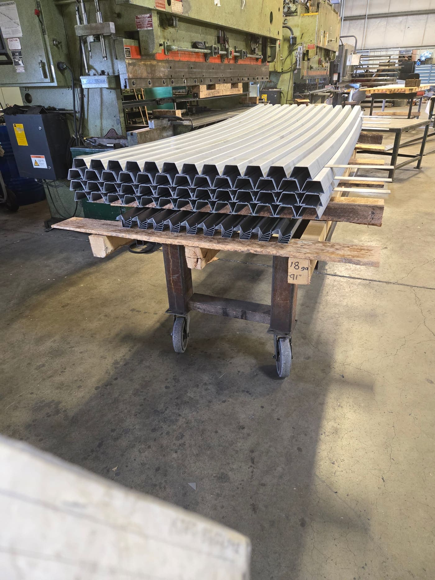 Stack of formed aluminium channel profiles on a shop cart