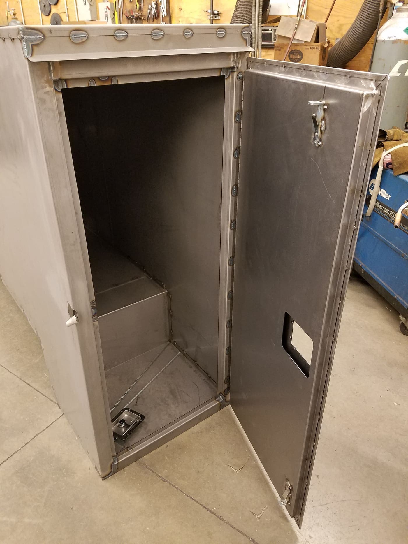 Tall stainless steel cabinet enclosure with access cut-out on the shop floor