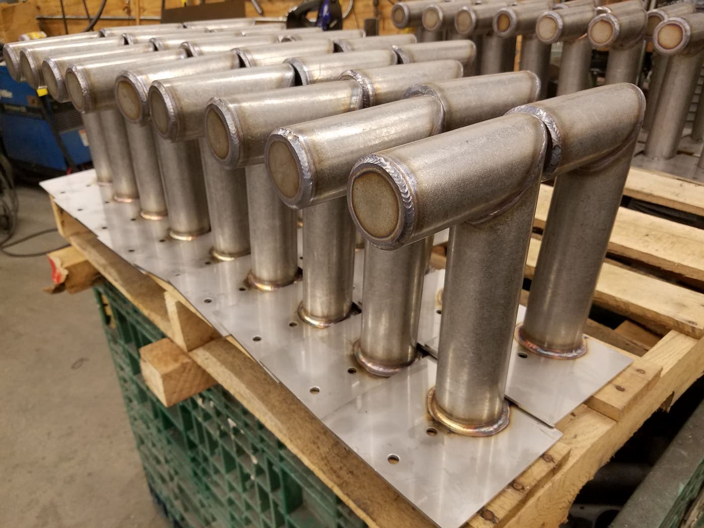 Production run of welded stainless tube assemblies with flanged ends stacked on a pallet